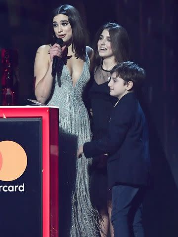 <p>Gareth Cattermole/Getty</p> Dua Lipa is seen onstage with her sister Rina and brother Gjin as she accepts the British Breakthrough award at The BRIT Awards 2018 on February 21, 2018 in London, England.