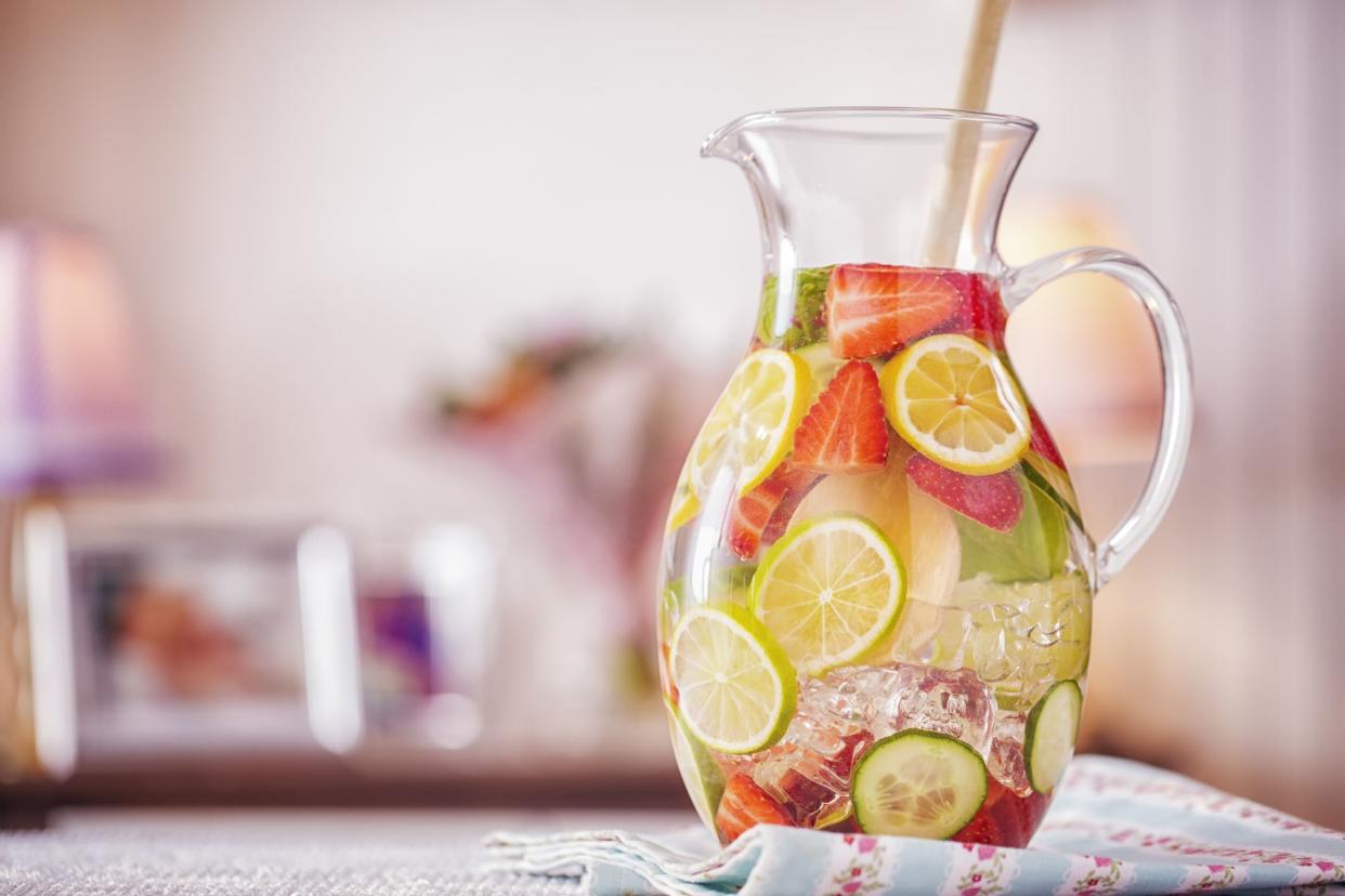 Water infused with fresh strawberries, lime, lemon and basil served in a glass.