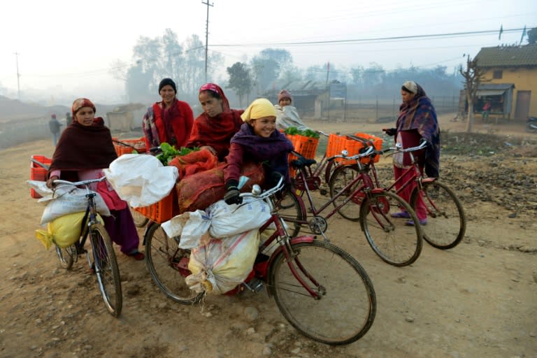 Female vendors, using their bicycles to carry their vegetables, arrive to sell their wares at a market in Nepal this February