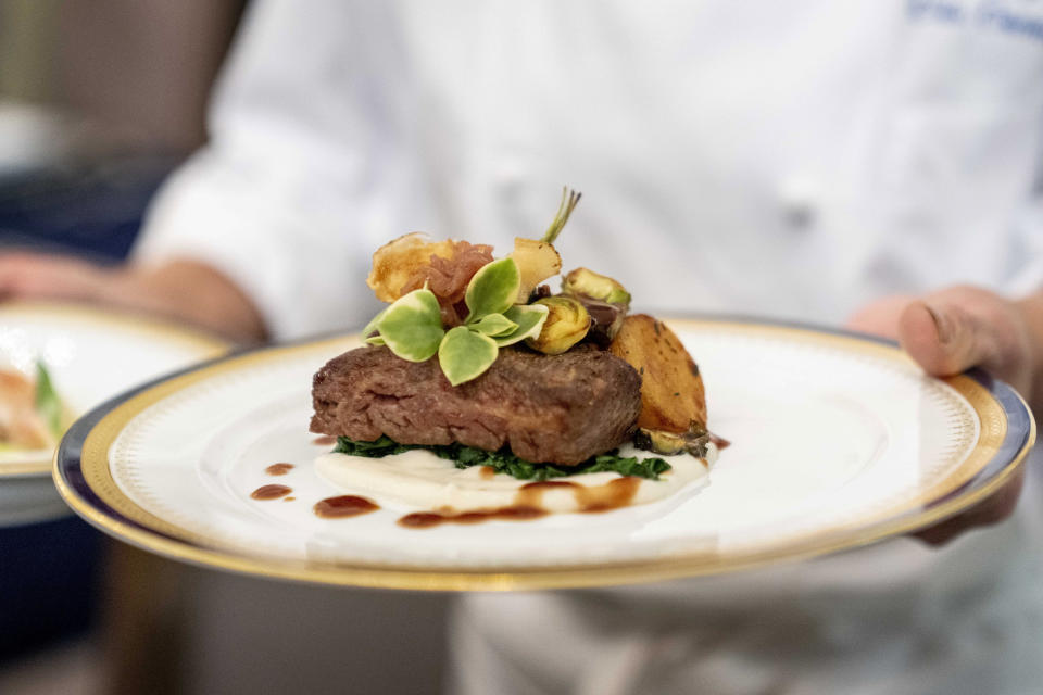 White House executive chef Cris Comerford holds a dish during a media preview for the State Dinner with President Joe Biden and French President Emmanuel Macron in the State Dining Room of the White House in Washington, Wednesday, Nov. 30, 2022. The dinner will include a butter poached Maine lobster, beef with shallot marmalade, American artisanal cheeses, and an orange chiffon cake for desert. (AP Photo/Andrew Harnik)