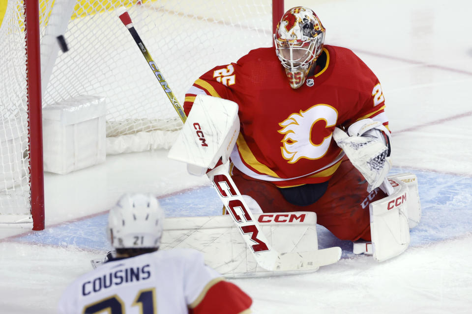 Calgary Flames goalie Jacob Markstrom, right, stops a shot by Florida Panthers center Nick Cousins, left, during second-period NHL hockey game action in Calgary, Alberta, Monday, Dec. 18, 2023. (Larry MacDougal/The Canadian Press via AP)