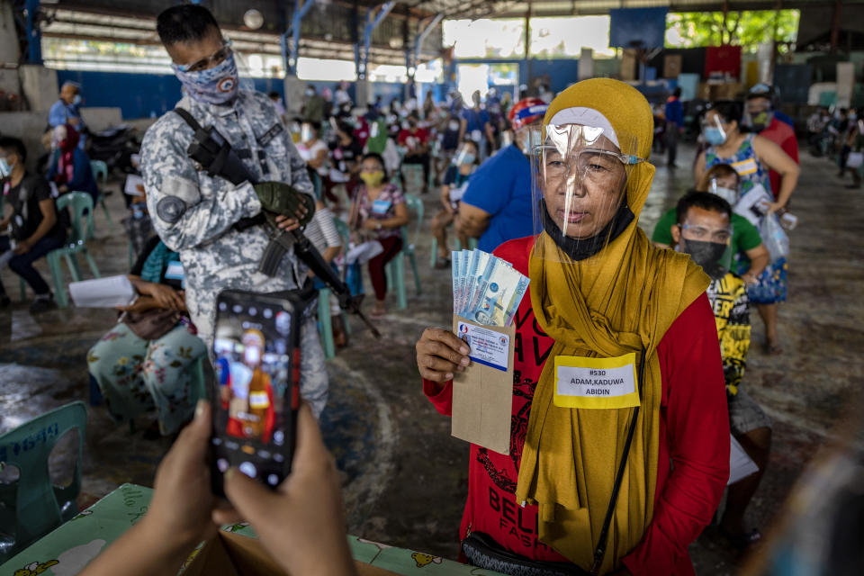 A social worker takes a picture of a resident receiving cash aid on April 7,2021 in Manila, Philippines. Each resident is entitled to 1,000 pesos ($20), with a limit of 4,000 pesos ($80) per household. Some 24 million people in Manila and nearby provinces remain under strict lockdown, the longest in the world, as the worst COVID-19 surge in Southeast Asia continues to hammer the country's healthcare system. (Photo by Ezra Acayan/Getty Images)