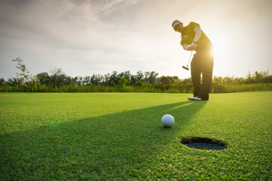 Golfer locht einen Ball ein.