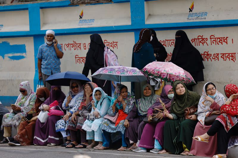 Parents wait outside a school to receive their children as schools reopen after the fall in temperature, in Dhaka