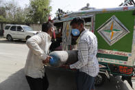 People carry a medical oxygen cylinder at a charging station on the outskirts of Prayagraj, India, Friday, April 23, 2021. India put oxygen tankers on special express trains as major hospitals in New Delhi on Friday begged on social media for more supplies to save COVID-19 patients who are struggling to breathe. India's underfunded health system is tattering as the world's worst coronavirus surge wears out the nation, which set another global record in daily infections for a second straight day with 332,730. (AP Photo/Rajesh Kumar Singh)