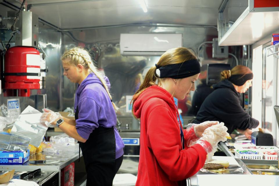 From left, Jenna, Kylee and Toni Heath putting together nachos, a cheeseburger and taking orders inside the JT's American Food on the Fly truck on Saturday, April 1, 2023.