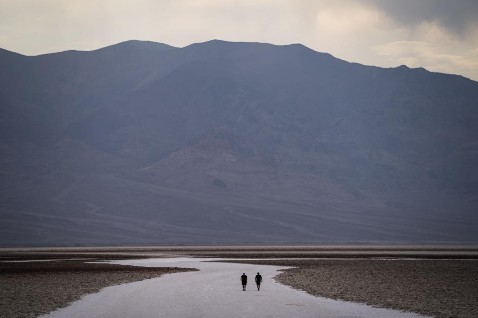 People walk on salt flats in Badwater Basin, Sunday, July 11, 2021, in Death Valley National Park, Calif. Death Valley, in southeastern California's Mojave Desert, reached 128 degrees Fahrenheit (53 Celsius) a day earlier, according to the National Weather Service's reading at Furnace Creek. The shockingly high temperature was actually lower than the previous day, when the location reached 130 F (54 C). (AP Photo/John Locher)