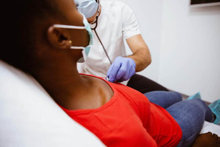 Medical professional treating patient with stethoscope. Healthcare worker is examining woman's heartbeat. They are in doctor's office.