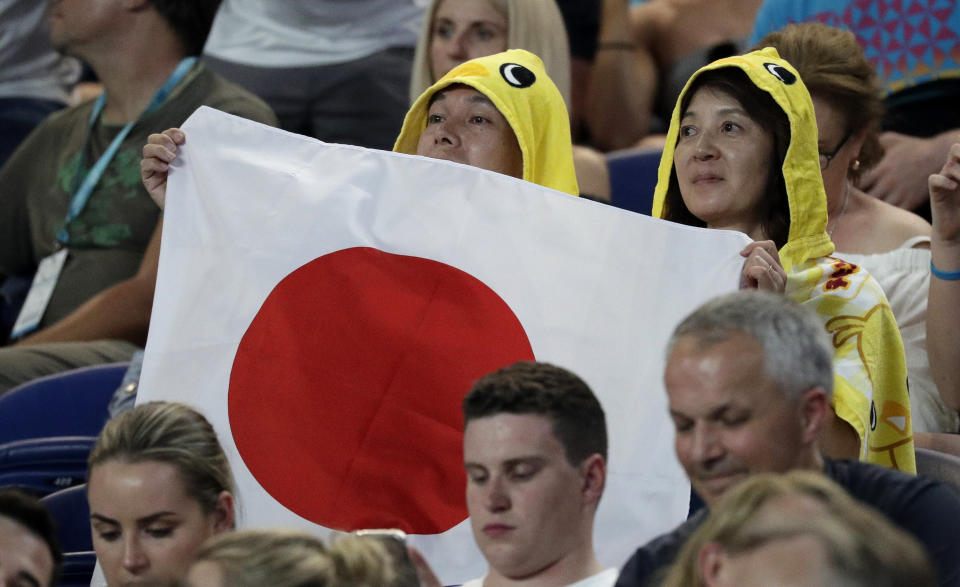 Supporters of Japan's Naomi Osaka hold up a flag during her first round match against Poland's Magda Linette at the Australian Open tennis championships in Melbourne, Australia, Tuesday, Jan. 15, 2019. (AP Photo/Kin Cheung)