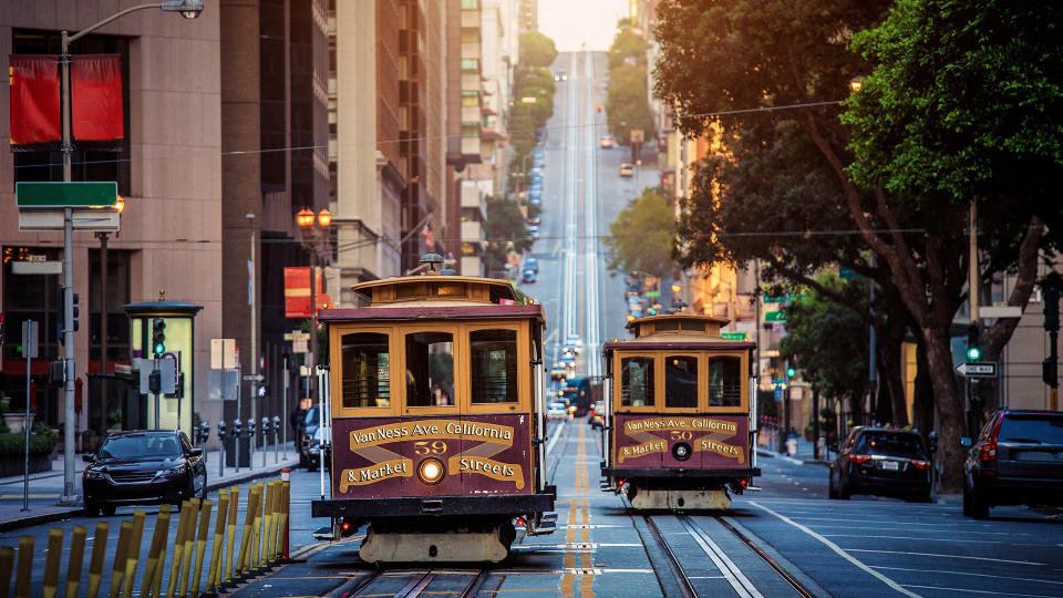 Classic view of historic traditional Cable Cars riding on famous California Street in morning light at sunrise with retro vintage style cross processing filter effect, San Francisco, California, USA.