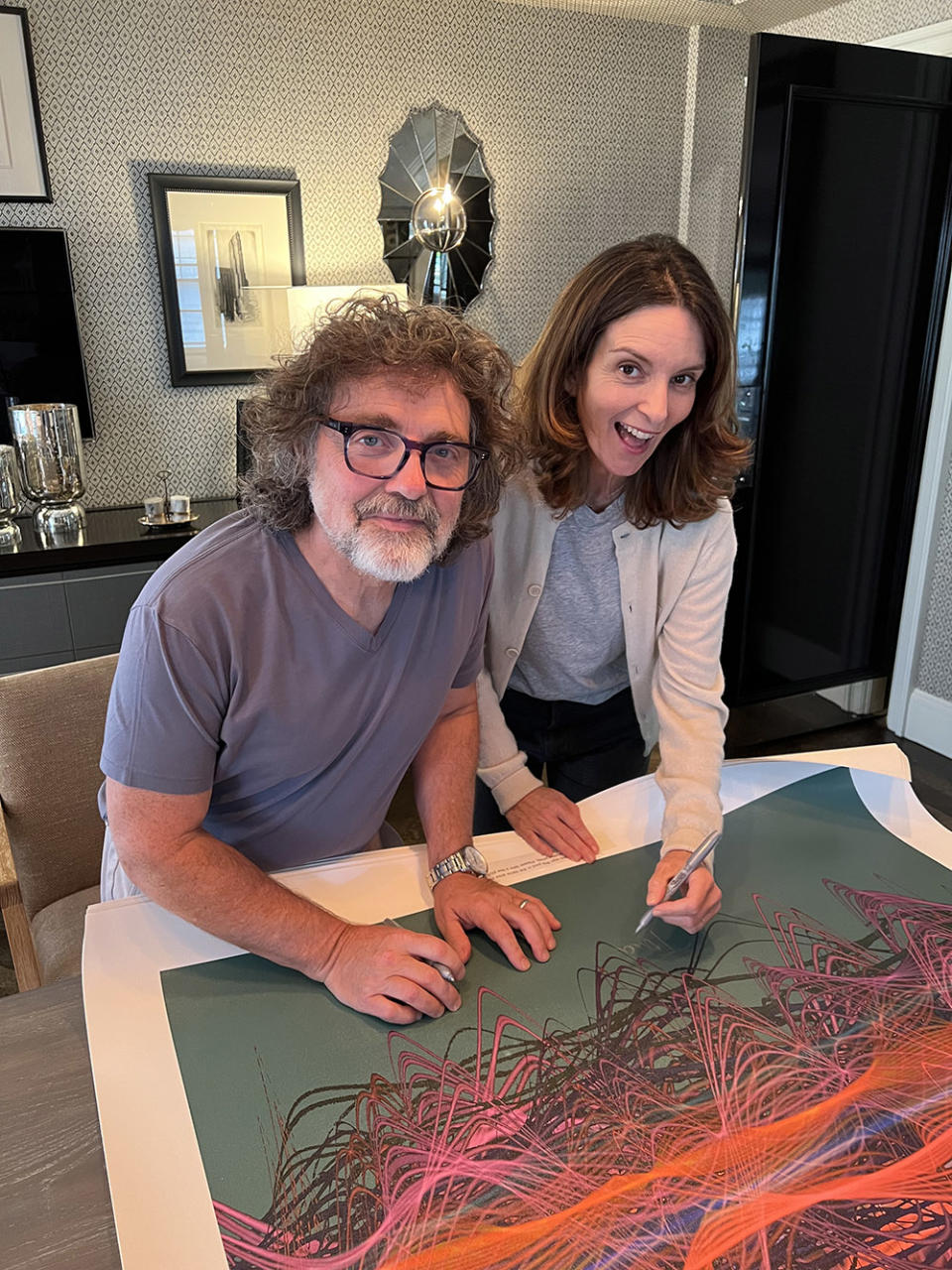 Tina Fey and husband Jeff Richmond sign limited-edition 30 Rock soundwaves artwork to fundraise for SAG-AFTRA Foundation. The duo autographed a limited edition of canvases created from the actual sound waves of the 30 Rock theme song, which was composed by Richmond, and all profits from the artwork will be donated. The artwork is made by artist Tim Wakfield, founder of Soundwaves Art Foundation.