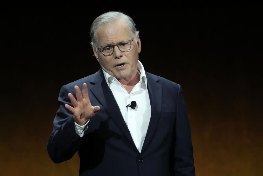 David Zaslav speaks and gestures while wearing a dark suit and glasses.