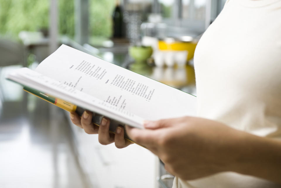 A person reading a recipe fro a cookbook