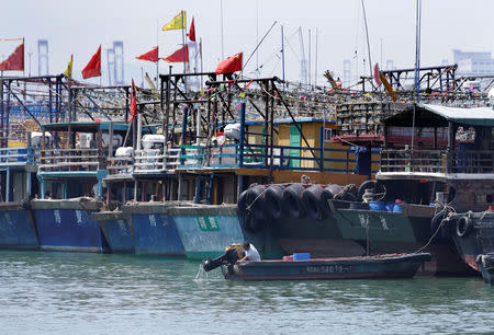 A fisherman lifts the propeller up next to anchored boats at a fishing harbour, as Typhoon Mangkhut approaches, in Shenzhen, China September 15, 2018. REUTERS/Jason Lee