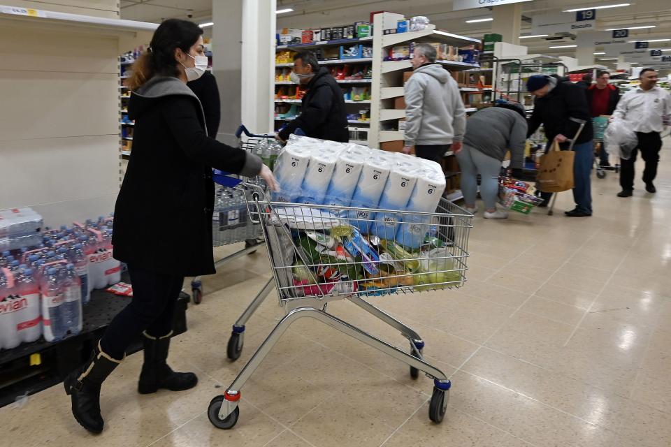 A woman wearing a mask buys toilet paper at a supermarket in London on March 14, 2020, as consumers worry about product shortages, leading to the stockpiling of household products due to the outbreak of the novel coronavirus COVID-19. - British Prime Minister Boris Johnson, who has faced criticism for his country's light touch approach to tackling the coronavirus outbreak, is preparing to review its approach and ban mass gatherings, according to government sources Saturday. (Photo by JUSTIN TALLIS / AFP) (Photo by JUSTIN TALLIS/AFP via Getty Images)