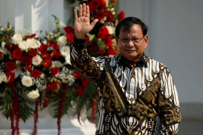 Newly appointed Indonesian Defense Minister Prabowo Subianto, who was the former rival of Indonesian President Joko Widodo in April's election, waves during the announcement of the new cabinet at the Merdeka Palace in Jakarta