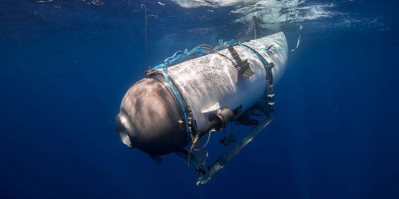 A side view of the Titan submersible, a large white cylindrical vessel with a rounded grey front that has a single porthole in water.