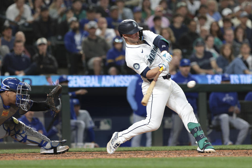 Seattle Mariners' Ty France hits a single next to Kansas City Royals catcher Salvador Perez during the eighth inning of a baseball game Tuesday, May 14, 2024, in Seattle. (AP Photo/Jason Redmond)