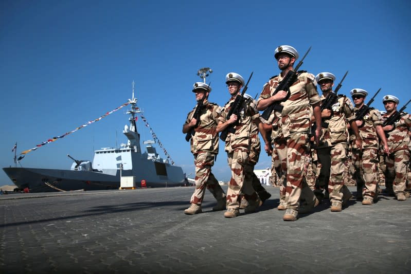 Members of the French Armed Forces march past the French frigate Courbet while taking part in a military cermony at the French Naval Base in Abu Dhabi