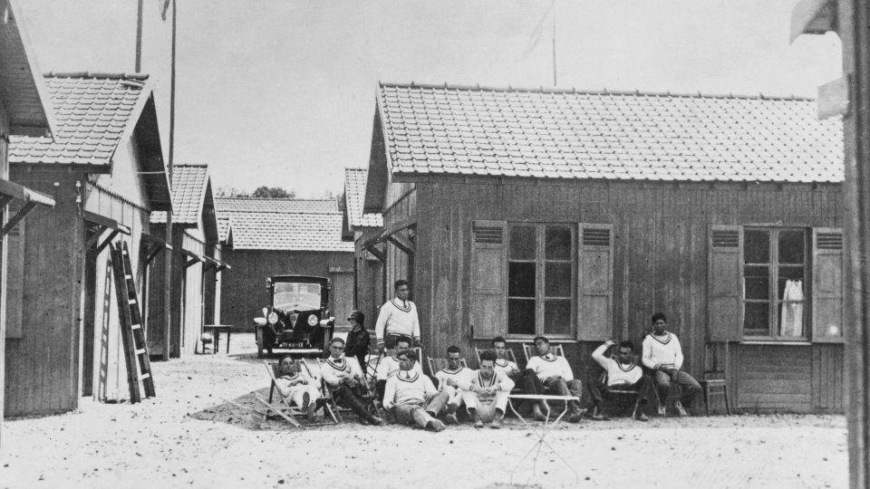 Athletes sitting in front of a cabin in the Olympic Village at the 1924 Summer Olympics in Paris, France. The 1924 Games were the first Games to have an Olympic Village, with a number of cabins built near the stadium to accommodate visiting athletes. - Topical Press/Hulton Archive/Getty Images