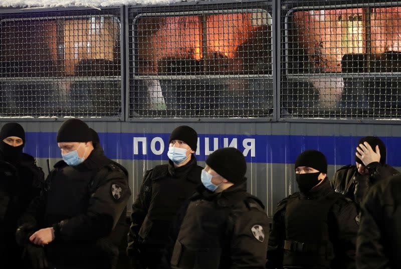 Law enforcement officers stand next to a police van during a rally to protest the detainment of Russian opposition leader Navalny, in Saint Petersburg