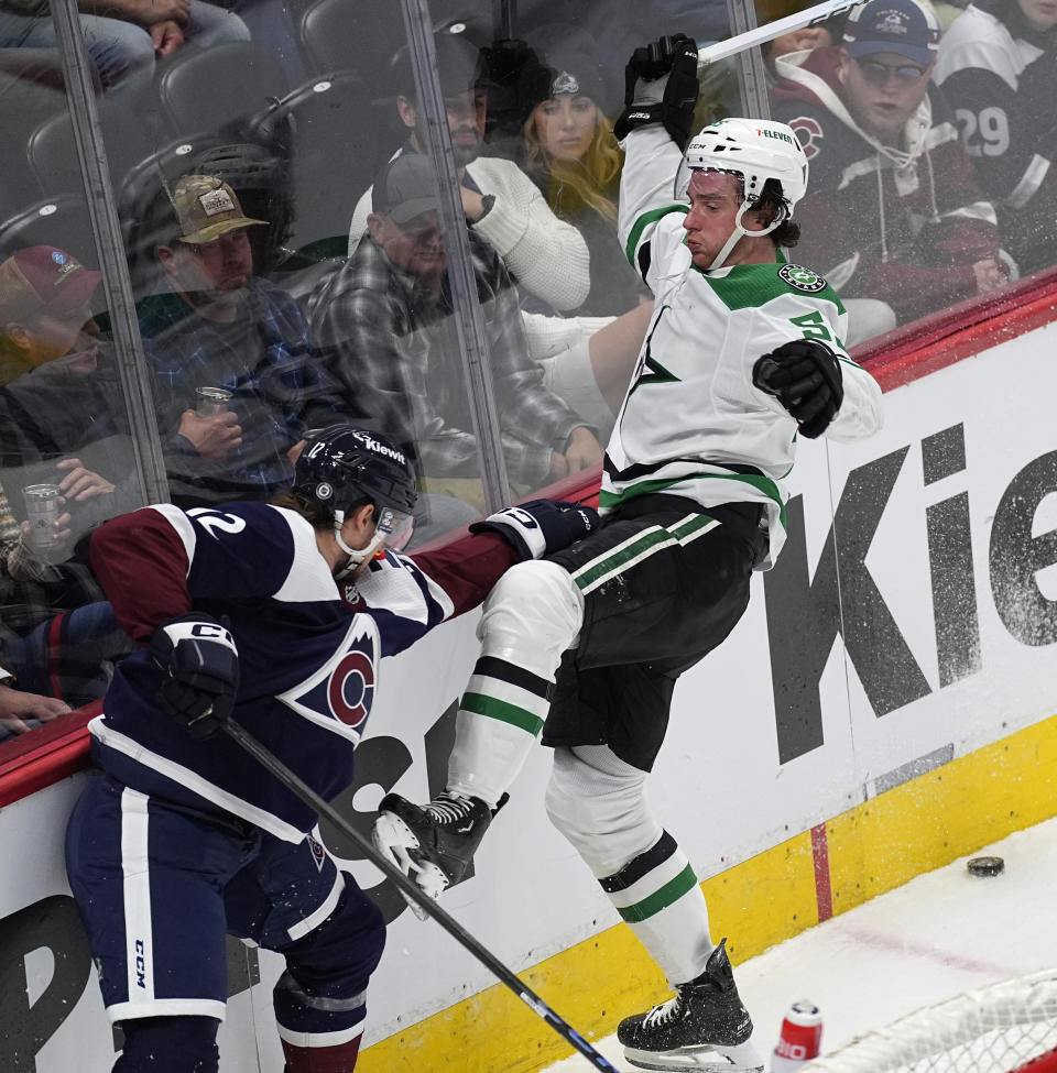 Dallas Stars defenseman Thomas Harley, right, loses his balance while trying to control the puck as Colorado Avalanche right wing Brandon Duhaime defends in the third period of an NHL hockey game Sunday, April 7, 2024, in Denver. (AP Photo/David Zalubowski)