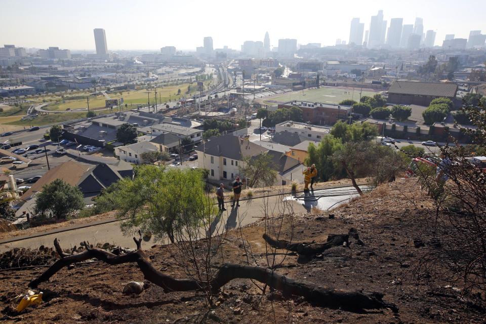 FILE - In this Dec. 14, 2017, file photo, Los Angeles Fire Department Arson Counter-Terrorism investigators check a burned-out homeless camp after a brush fire erupted in the hills in Elysian Park near downtown Los Angeles. Authorities say fires linked to homeless tents and camps are raising concern in Los Angeles, where they have claimed seven lives and caused tens of millions of dollars in damage to nearby businesses. The Los Angeles Times says the Fire Department handled 24 such fires a day in the first quarter of this year. (AP Photo/Damian Dovarganes, File)