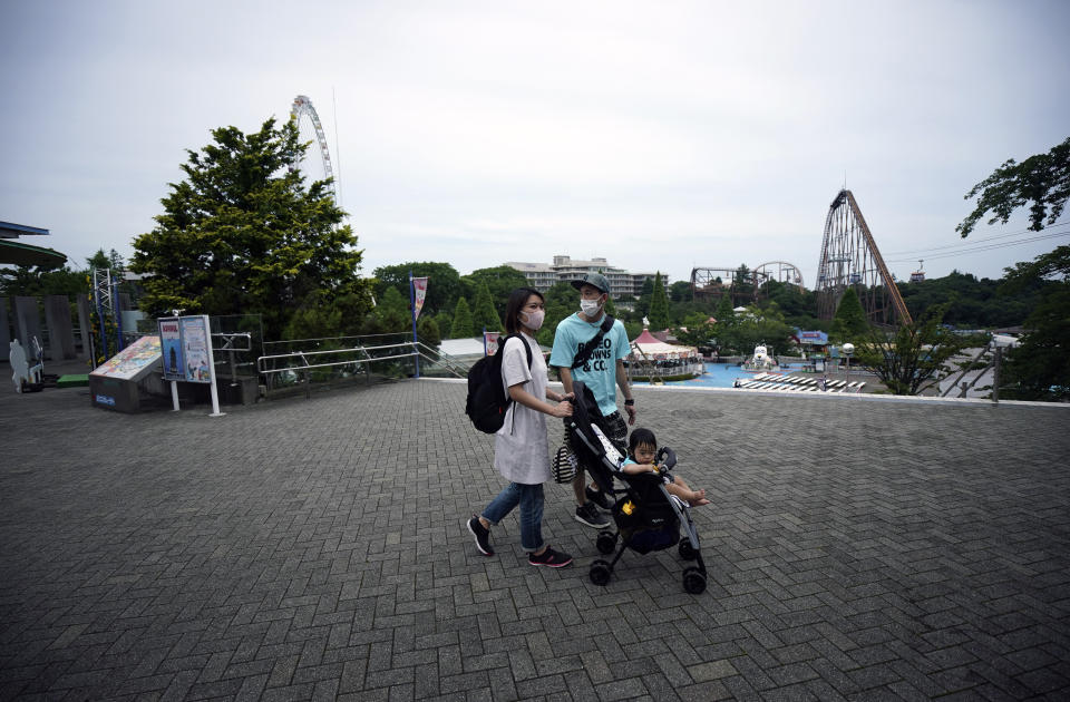 FILE - In this June 16, 2020, file photo, a family walks at the recently reopened Yomiuriland amusement park in Tokyo. Japan’s economy is opening cautiously, with social-distancing restrictions amid the coronavirus pandemic. (AP Photo/Eugene Hoshiko, File)