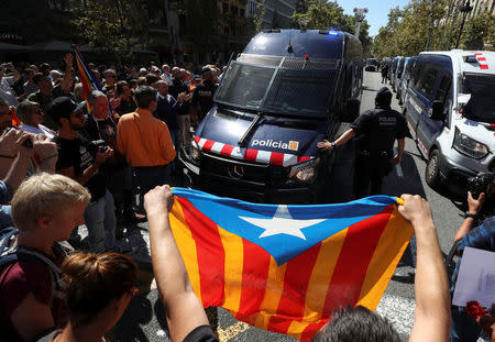 A protestor holds up an Estelada (Catalan separatist flag) in front of a Catalan police van outside the Catalan region's economy ministry building during a raid by Spanish police on several government offices, in Barcelona, Spain, September 20, 2017. REUTERS/Albert Gea