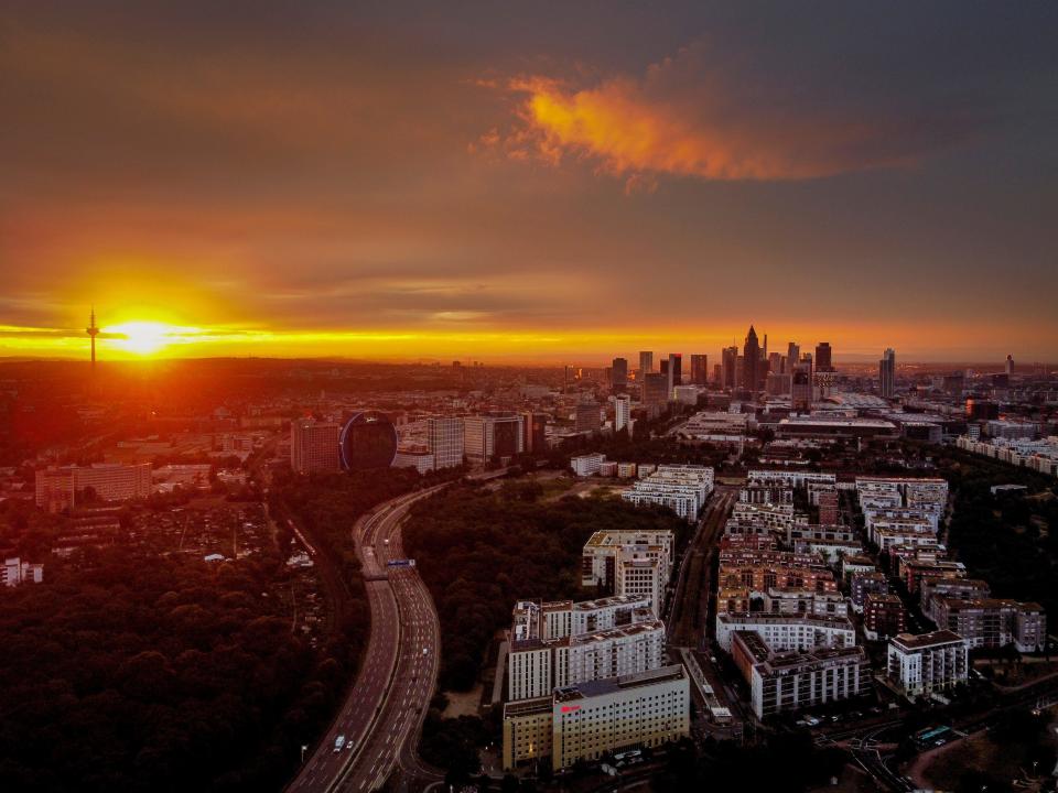 The sun rises over Frankfurt, Germany, with the buildings of the banking district at right, early Thursday, July 2, 2020. (AP Photo/Michael Probst)