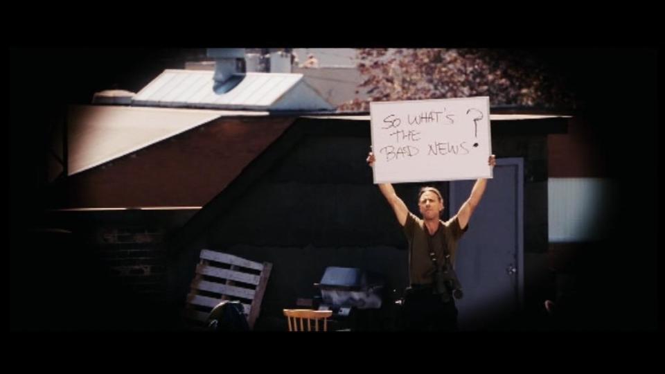 Man holds up sign with the words "So what's the bad news?"