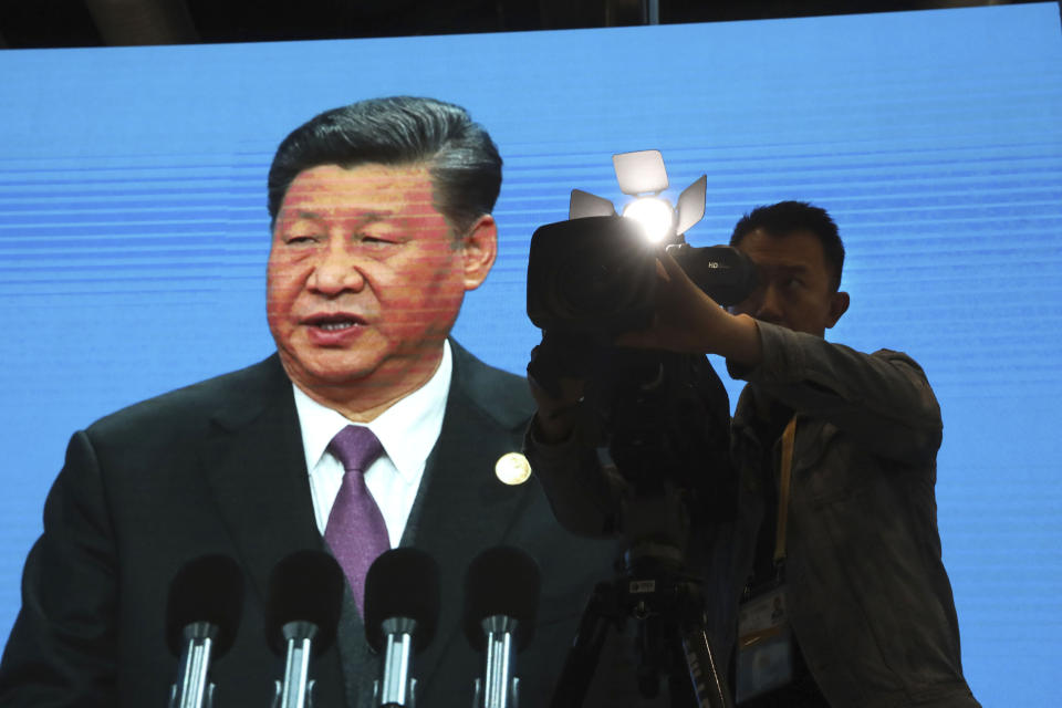 A cameraman films near a screen live broadcasting Chinese President Xi Jinping opening the Second Belt and Road Forum in Beijing Friday, April 26, 2019. The event celebrating the push for China-backed road, port and rail-building projects across the developing world, President Xi Jinping's signature foreign policy initiative, is one of Beijing's biggest of the year. (AP Photo/Ng Han Guan)