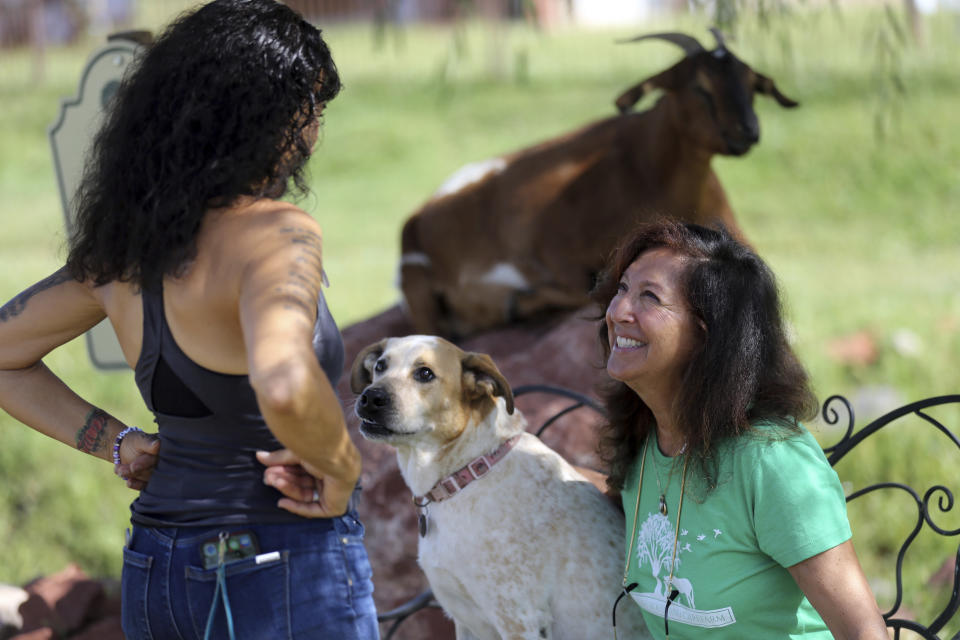 Joanne Cacciatore, left, talks with Suzy Elghanayan, as dog Perseverance, aka "Percy," watches at the Selah Carefarm in Cornville, Ariz., Oct. 4, 2022. While most who come to Selah take part in counseling sessions, Joanne Cacciatore, who runs the site, believes visitors’ experiences with the animals can be just as transformative. (AP Photo/Dario Lopez-Mills)