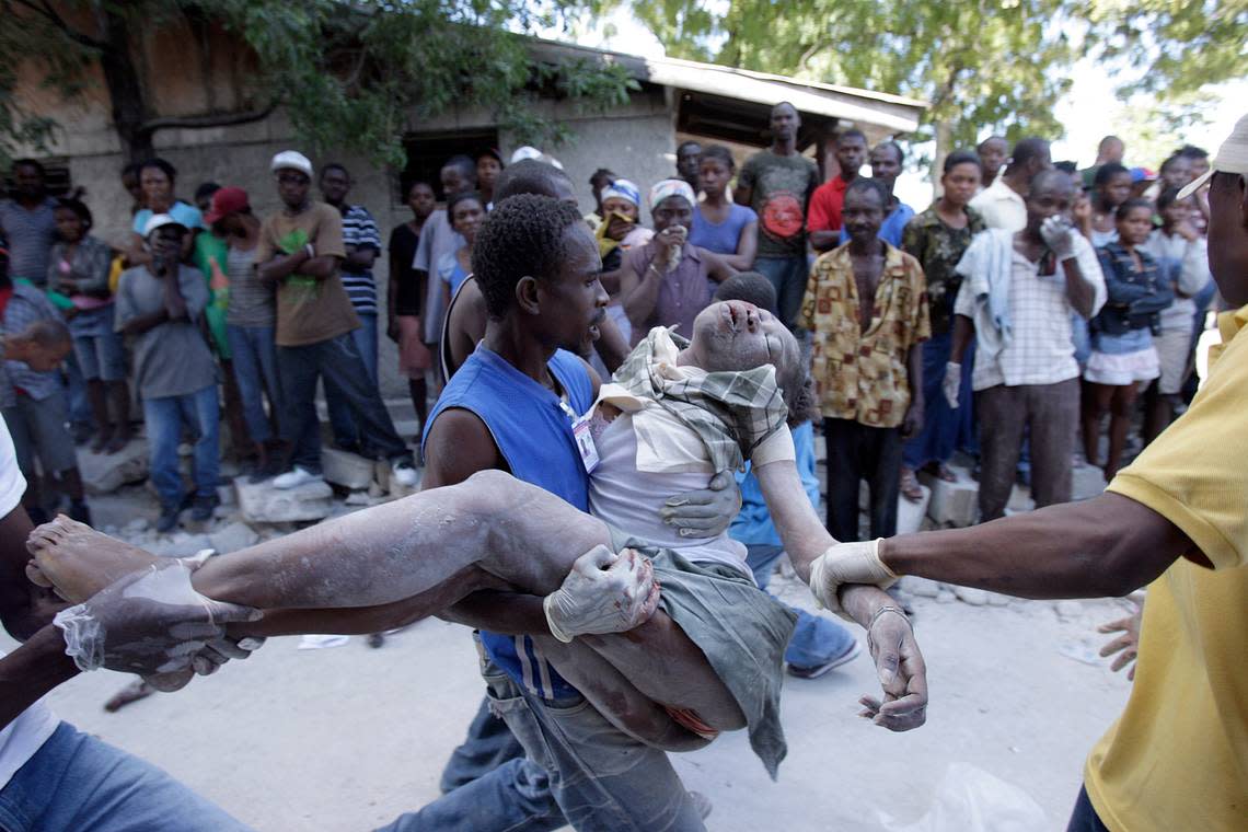 Destruction grips Haiti and the capital city of Port-au-Prince the day after an earthquake rattled the country Wednesday Jan. 13, 2010. Men remove the battered body of a young woman from the rubble.