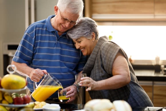 Couple in their 70s pouring orange juice