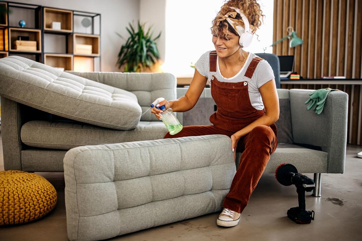 Cleaner doing deep washing of  sofa with professional equipment