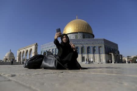 Palestinian Nura Hassan, 17, from the West Bank town of Bethlehem, takes a selfie photo in front of the Dome of the Rock on the compound known to Muslims as Noble Sanctuary and to Jews as Temple Mount, in Jerusalem's Old City, during the holy month of Ramadan, June 29, 2015. REUTERS/Ammar Awad