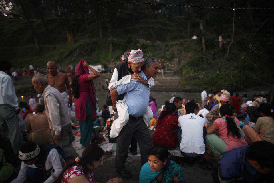 A Nepalese man carries his father to perform rituals during Kuse Aunsi, or Nepalese Fathers day at the Gokarneshwar Hindu temple in Katmandu, Nepal, Thursday, Sept. 5, 2013. Kuse Aunsi is a unique Hindu festival of Nepal where fathers living as well as deceased are honored. On this day people perform rituals to pay tributes to their deceased fathers while those with living fathers show their appreciation with presents and sweets. (AP Photo/Niranjan Shrestha)