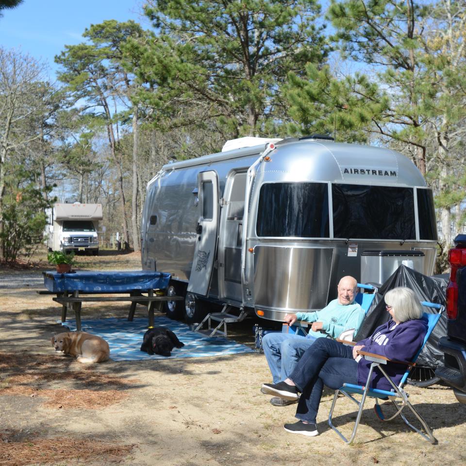 Bill and Sally O'Hearn take in the morning sun outside their camper with dogs Addie, left, and Angus during a week stay at the Atlantic Oaks Campground on Route 6 in Eastham, which opened for the season on May 1.