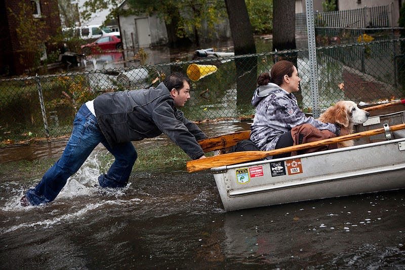 A man pushes a woman and a dog in a boat a boat after their neighborhood experienced flooding due to Hurricane Sandy, on October 30, 2012, in Little Ferry, New Jersey. 