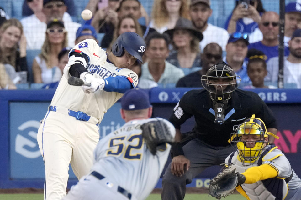 Los Angeles Dodgers' Shohei Ohtani, left, hits a solo home run as Milwaukee Brewers relief pitcher Bryan Hudson, second from left, and catcher William Contreras watch along with home plate umpire Edwin Moscoso during the eighth inning of a baseball game Saturday, July 6, 2024, in Los Angeles. (AP Photo/Mark J. Terrill)