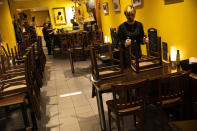 Staff of Spanish El Fontan restaurant tidy up before closing it down in Brussels, Sunday, Oct. 18, 2020. Faced with a resurgence of coronavirus cases, the Belgian government on Friday announced new restrictions to try to hold the disease in check, including a night-time curfew and the closure of cafes, bars and restaurants for a month. The measures will take effect on Monday, Oct. 19, 2020. (AP Photo/Francisco Seco)