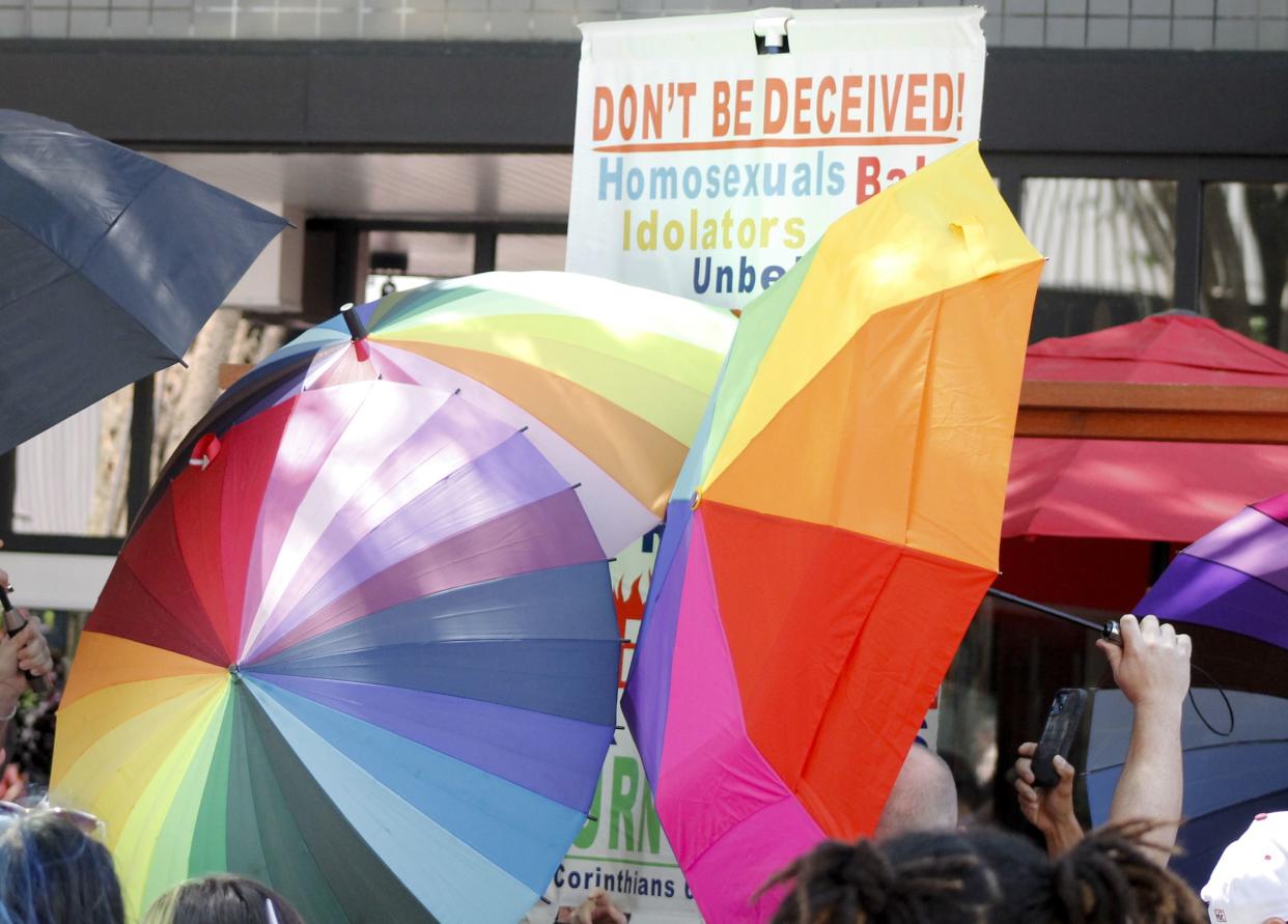 A sign-carrying anti-gay protester is surrounded by a sea of Pride umbrellas during the Pride parade in Winston-Salem, N.C., on June 18, 2022. 