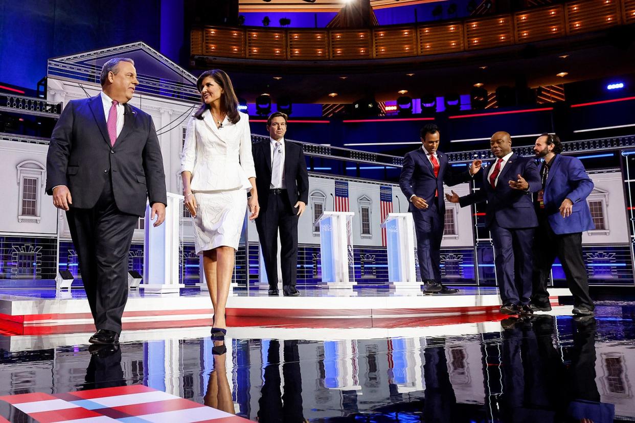 The candidates and a producer walking on NBC's set.