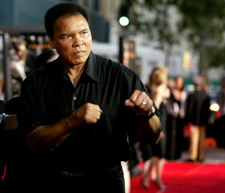 Boxing legend Muhammad Ali (R) jabs at photographers while arriving at the Orpheum Theatre for the premiere of the film "Collateral" in Los Angeles in this August 2, 2004 file photo. REUTERS/Robert Galbraith/File Photo - RTSFZ0G