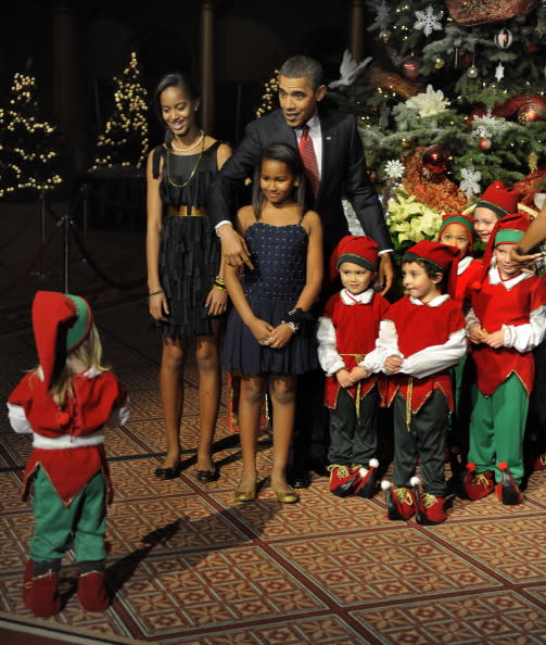 US President Barack Obama gestures to a wayward child to join the group of other children also dressed in Christmas elves costumes for a photo at a Christmas In Washington celebration at the Building Museum in Washington, DC, USA, 12 December 2010. Obama's daughters Malia and Sasha are at (L). ISP Pool Photo by Mike Theiler via EPA