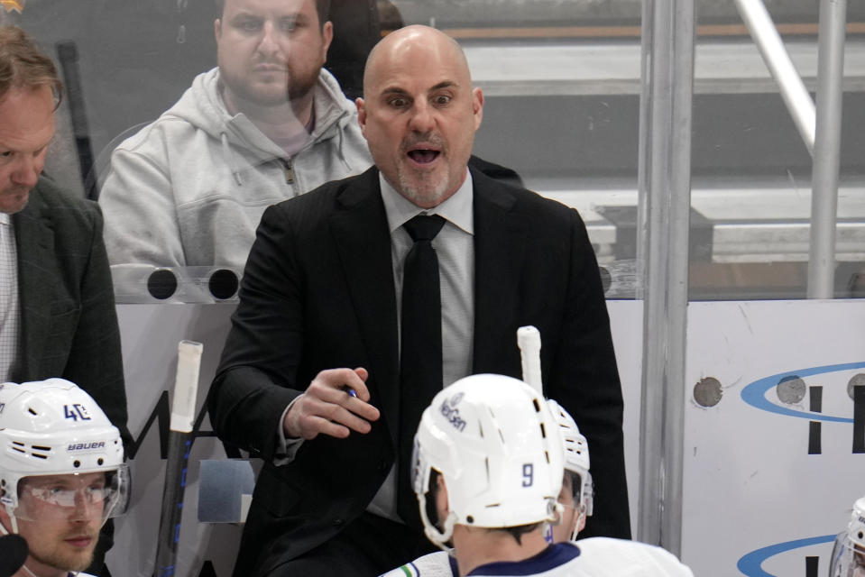 Vancouver Canucks coach Rick Tocchet gives instructions to J.T. Miller (9) and others during overtime period of the team's NHL hockey game against the Pittsburgh Penguins in Pittsburgh, Thursday, Jan. 11, 2024. (AP Photo/Gene J. Puskar)