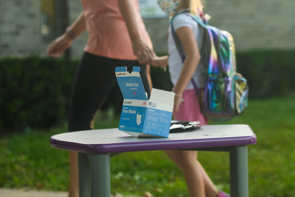 A box of face masks on a table outside of a school.