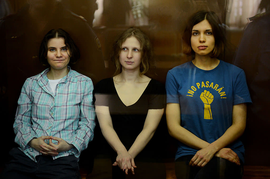 Pussy Riot members, from left, Maria Alyokhina, Yekaterina Samutsevich, and Nadezhda Tolokonnikova, sitting in a glass-walled Moscow court cage in 2012 for sentencing after their convictions for hooliganism motivated by religious hatred. The charges stemmed from the group’s “Punk Prayer” protest staged at Moscow’s Cathedral of Christ the Savior. (Credit: Natalia Kolesnikova/AFP via Gtty Images)