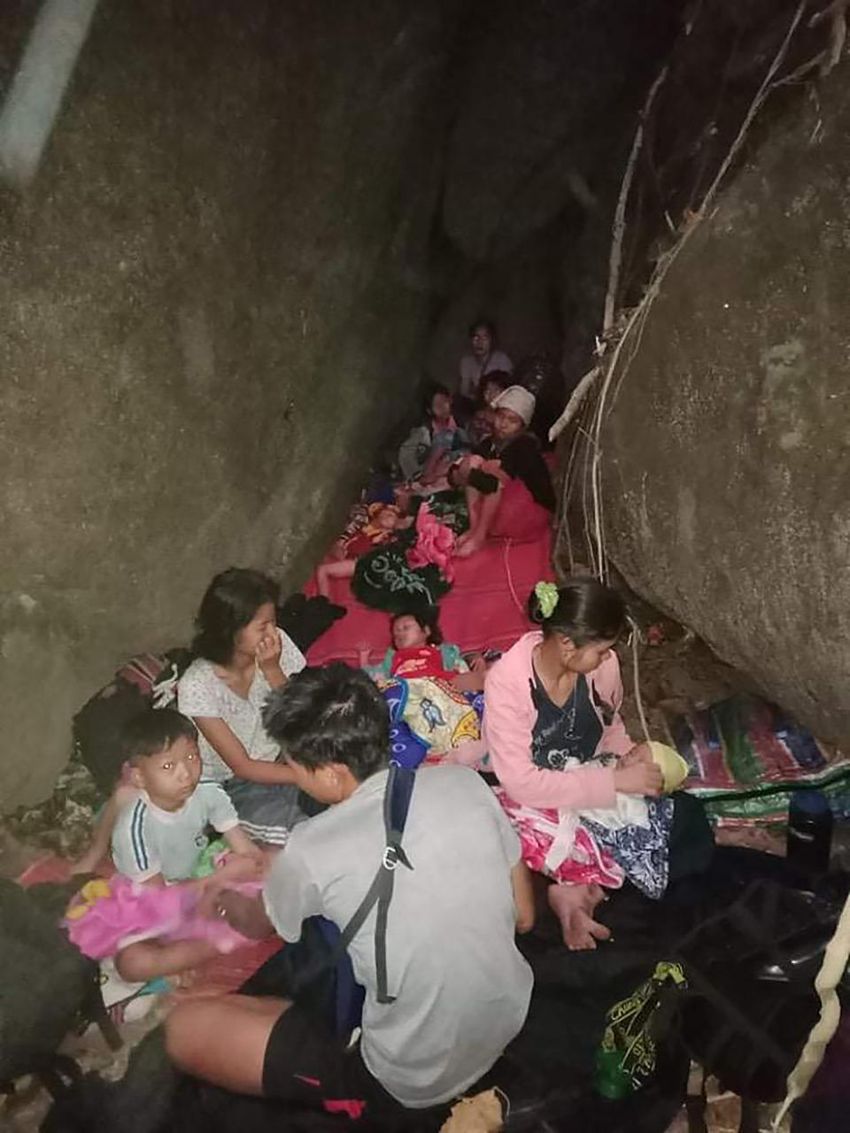 In this photo provided by Free Burma Rangers, villagers shelter in the open due to airstrikes, Saturday, March 27, 2021, in Deh Bu Noh, in Karen state, Myanmar. Myanmar military jets hit a village in Karen State, on Saturday night, killing a few people and wounding others, according to relief organizations.(Free Burma Rangers via AP)